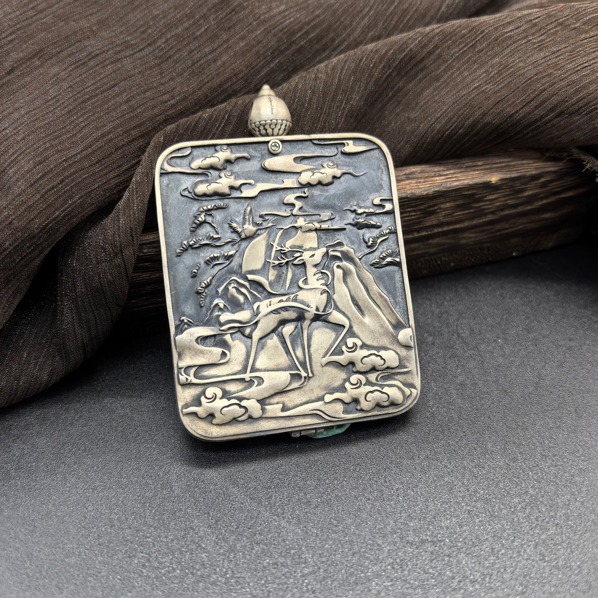 The Rekong Red Yellow Jambhala Thangka pendant displayed as a sacred amulet for wealth and fortune, embodying Buddhist tradition.
