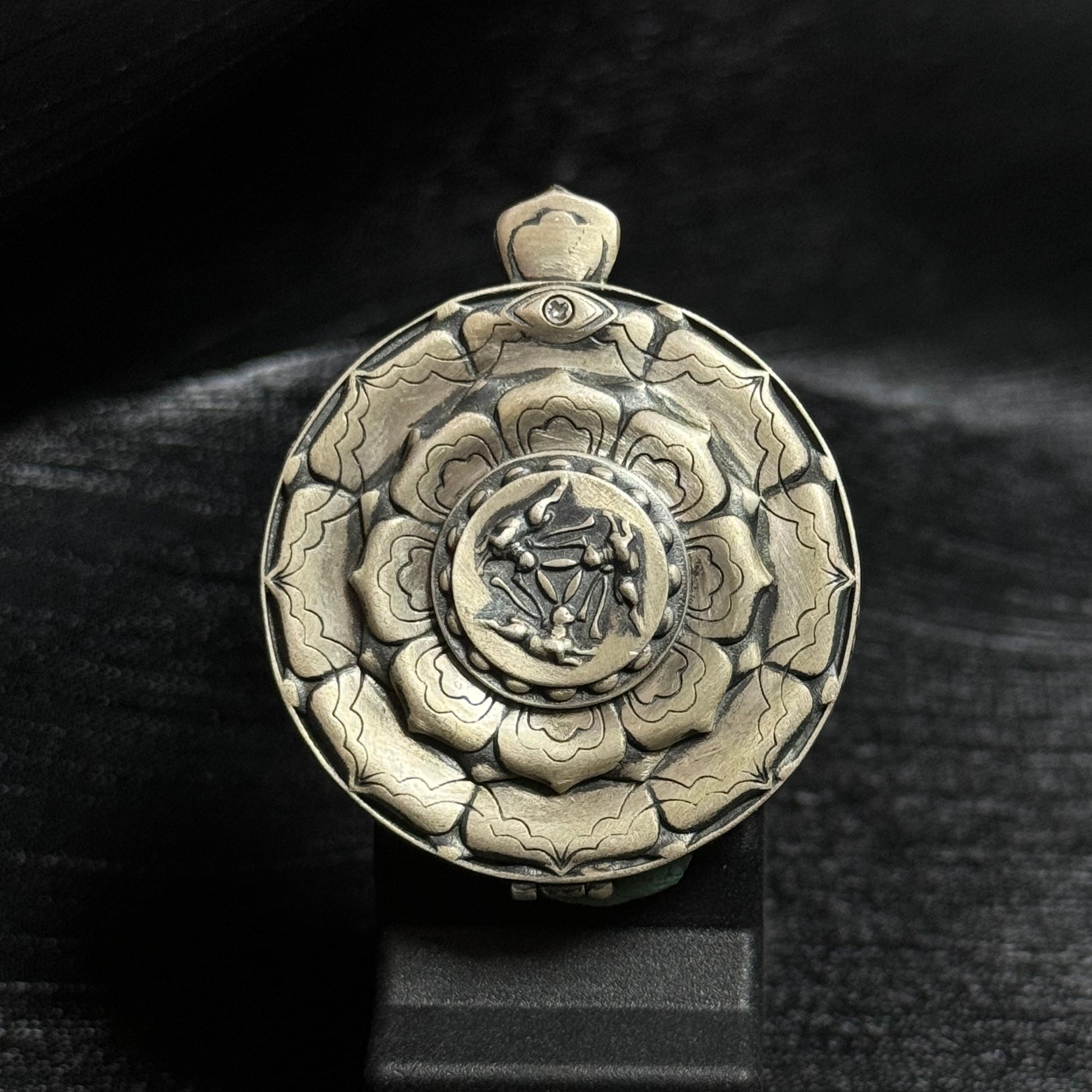 The Rekong Yellow Jambhala Thangka pendant displayed as a sacred amulet for wealth and blessing, embodying Buddhist tradition.
