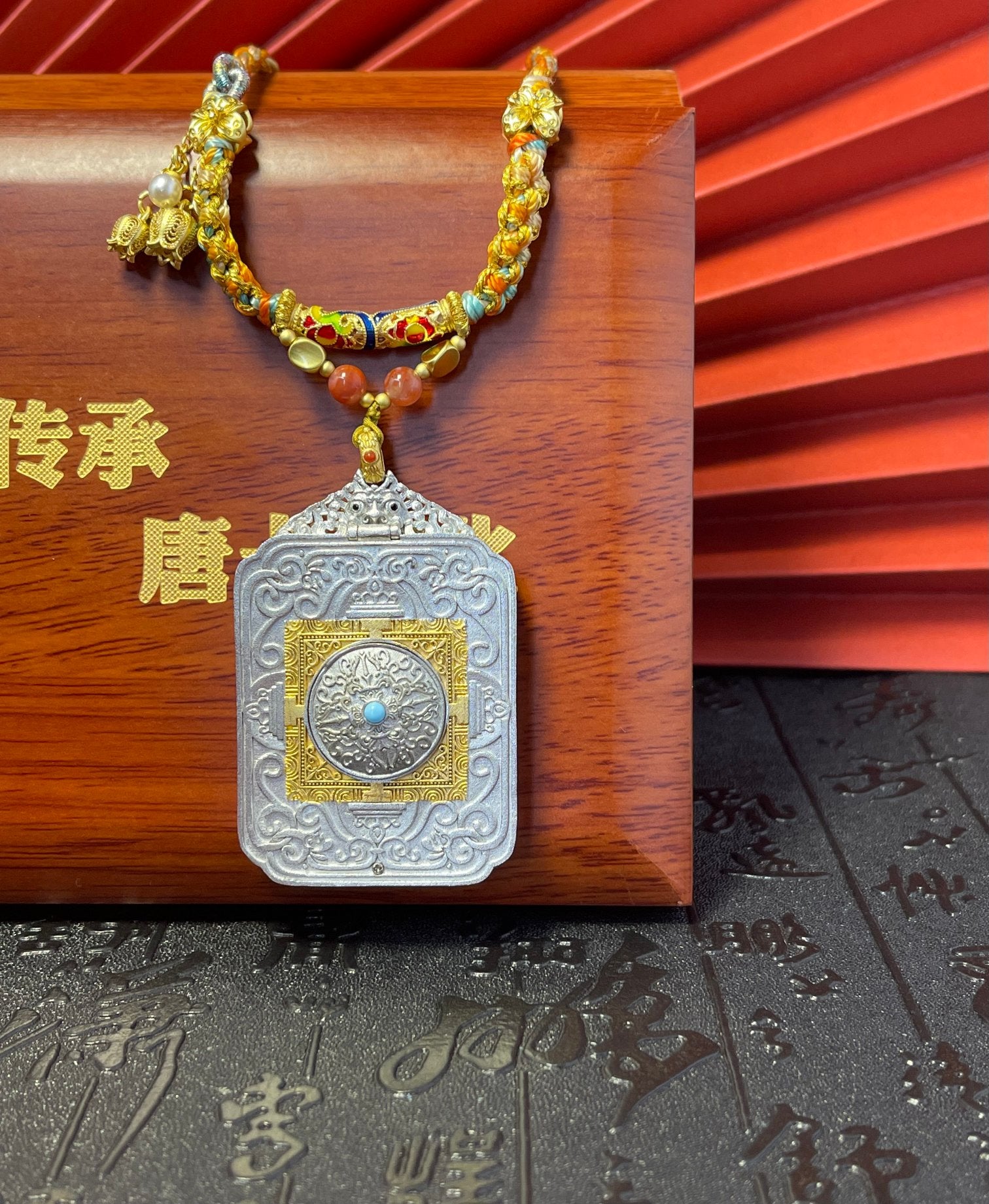 The Rekong Yellow Jambhala 3.5x4.5cm pendant with hand-woven cord displayed as an amulet for wealth and career.

