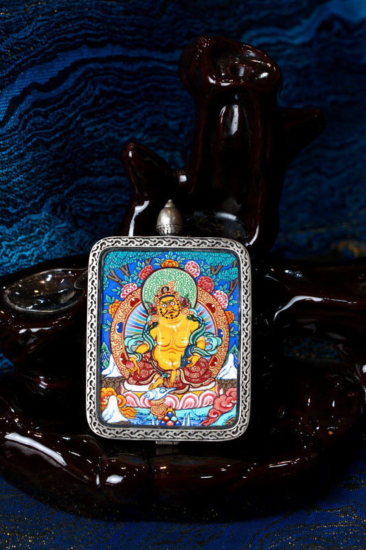 A high-end hand-painted Yellow Jambhala Thangka pendant from Regong, Qinghai, featuring the God of Wealth seated on a lotus throne, encased in a premium silver frame.