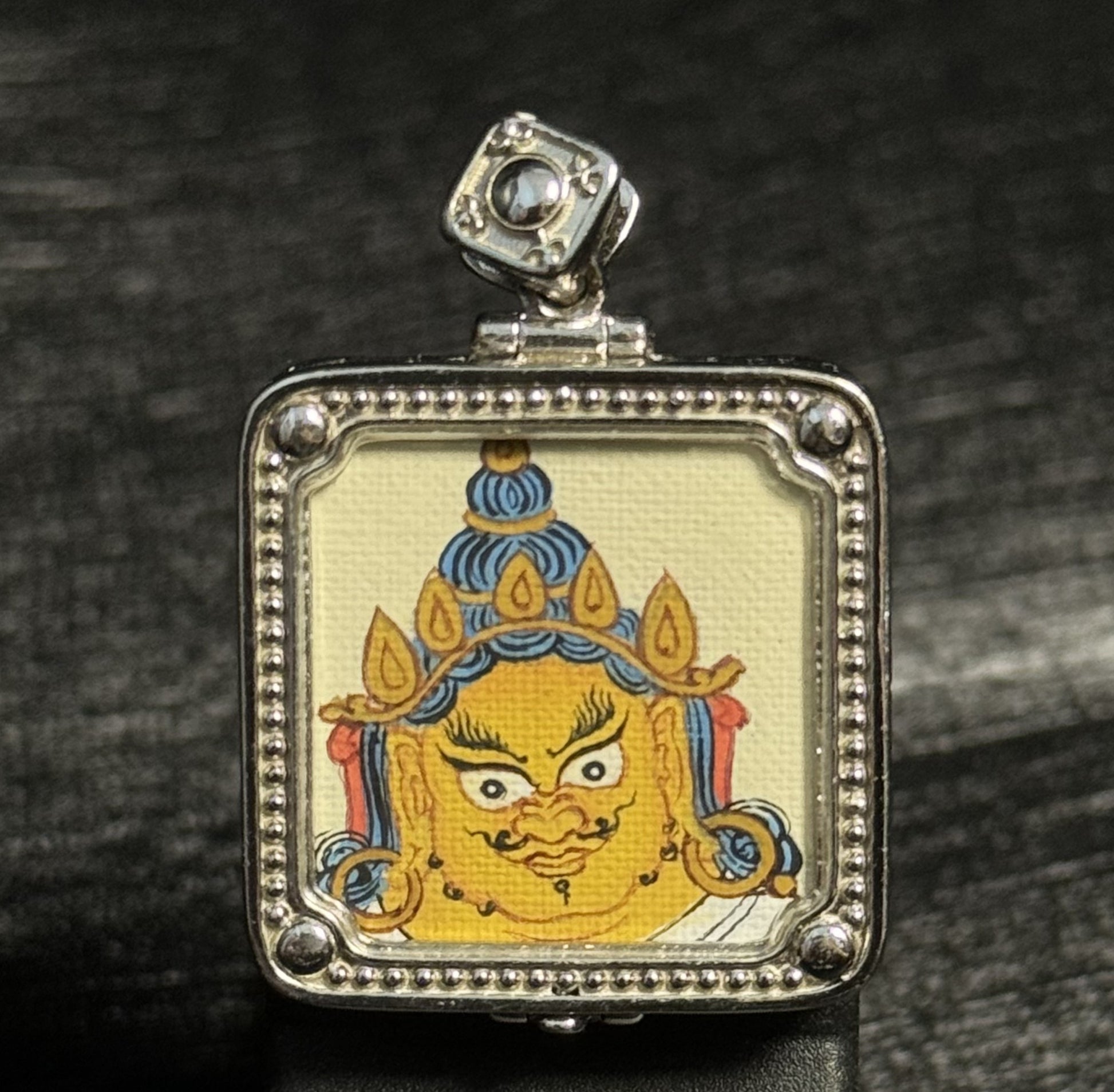A 2x2cm hand-painted Tibet Yellow Jambhala Thangka pendant featuring the King of Wealth, representing wealth and fortune in Buddhist tradition.

