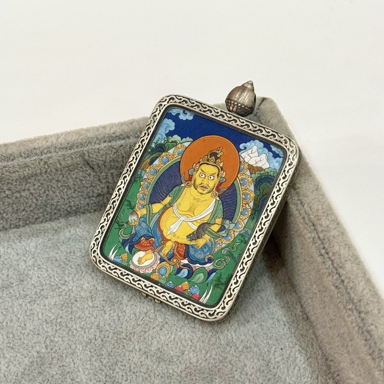  Hand-painted Tibet Miansa Yellow Jambhala Thangka pendant featuring the King of Wealth, encased in Dunhuang Nine-Color Deer silver case, representing prosperity and merit in Tibetan Buddhist tradition.
