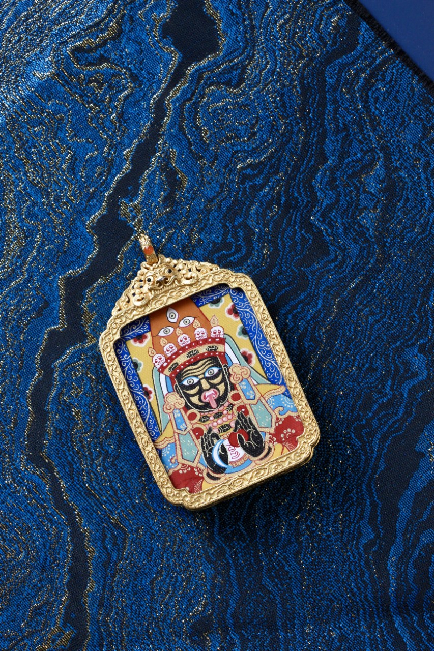 Tibetan Buddhist art thangka pendant showing Zaki Lhamo, symbolizing fortune, prosperity, and protective blessings.