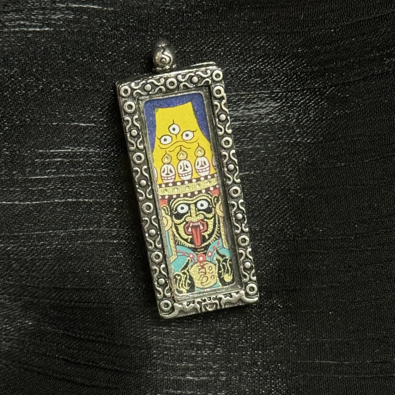 The Rebgong Buddha Head Zhagilamu Thangka pendant displayed as a sacred amulet for wealth and wishes fulfilled, embodying Tibetan Buddhist tradition.
