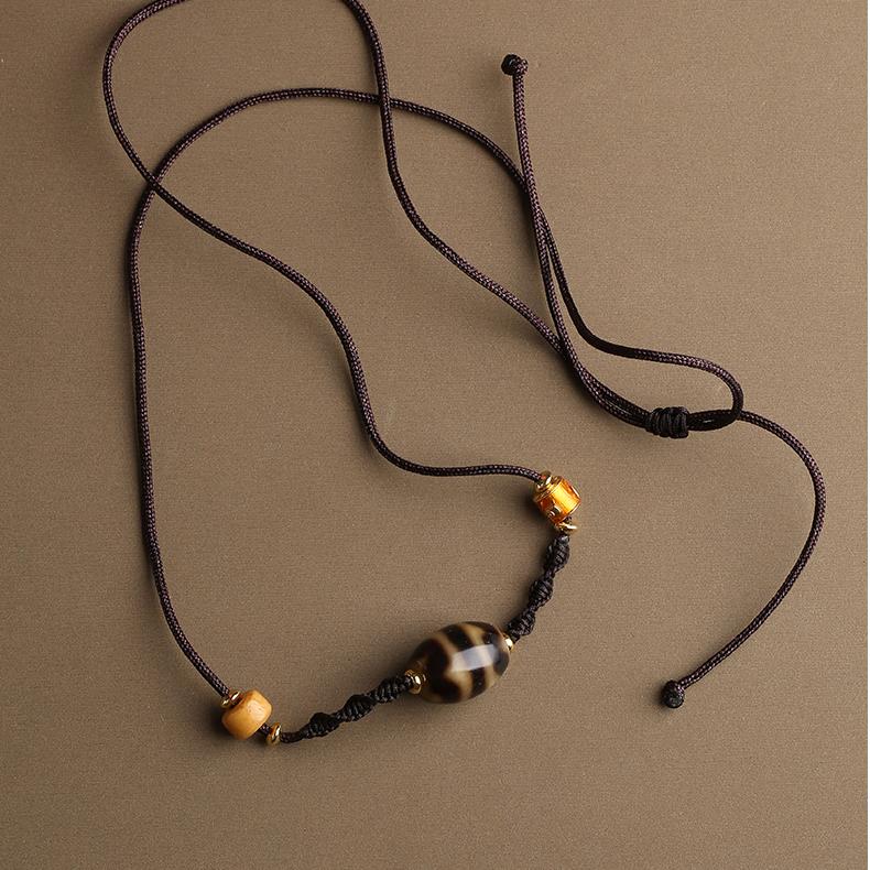 Handmade Tibetan Buddhist double tiger tooth Dzi pendant crafted with agate and carved bone.