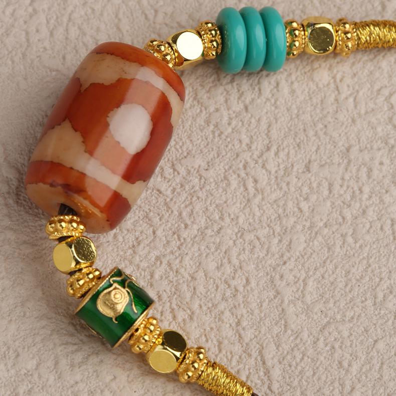Close-up of a Three-Eyes Dzi agate amulet, representing the balance of Body, Speech, and Mind, in a copper alloy bezel.