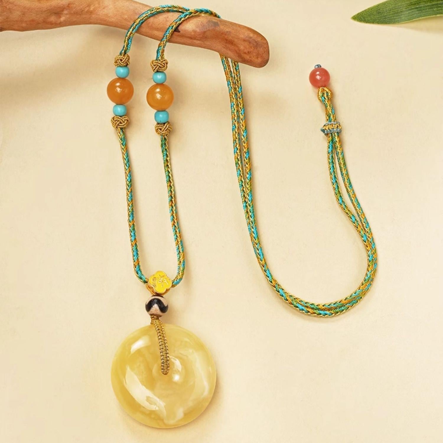 Handcrafted Tibetan amber pendant with tiger tooth Dzi bead, inspired by Buddhist talisman art