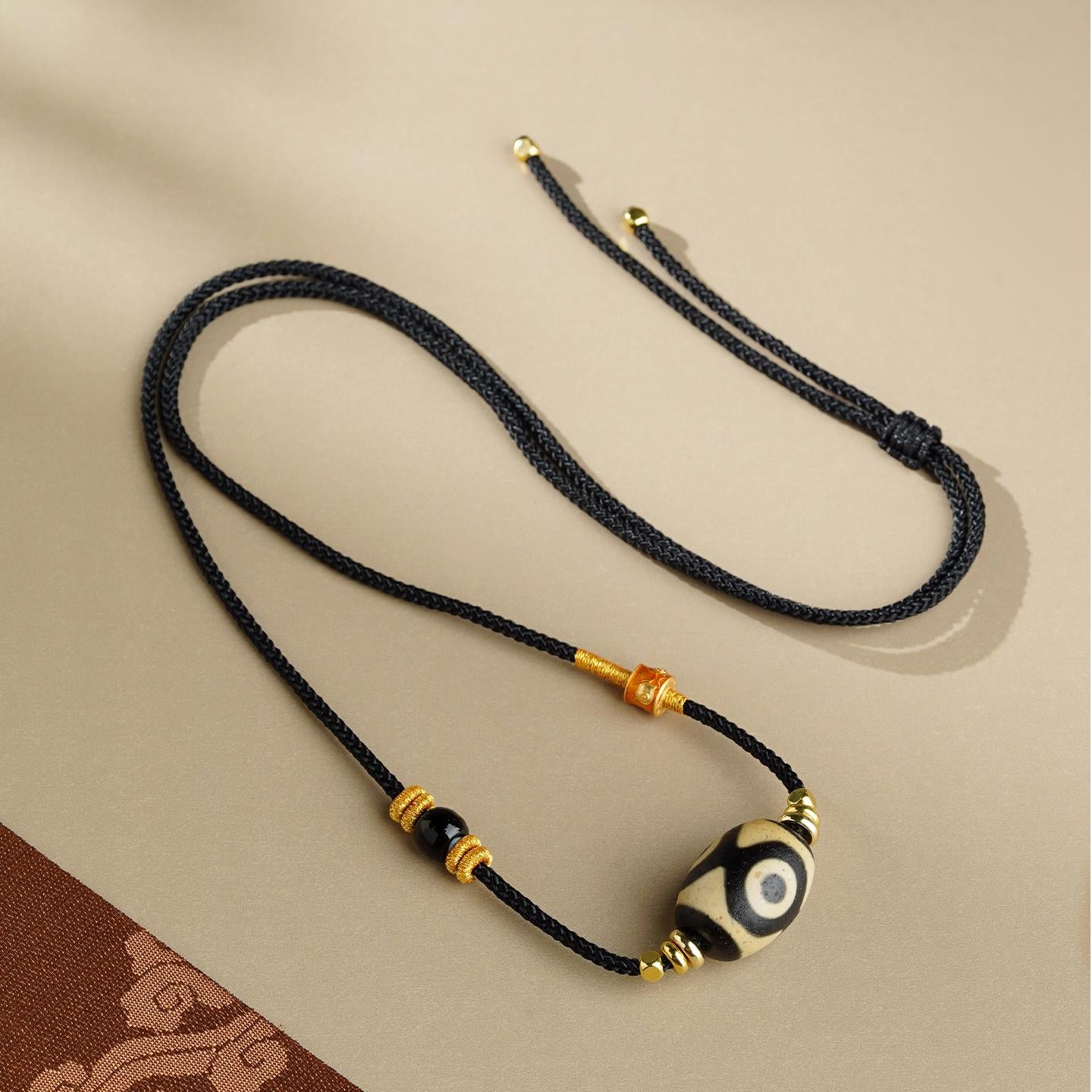 Handcrafted Tibetan Agate Dzi Bead Pendant featuring three eyes, representing wealth and spiritual clarity