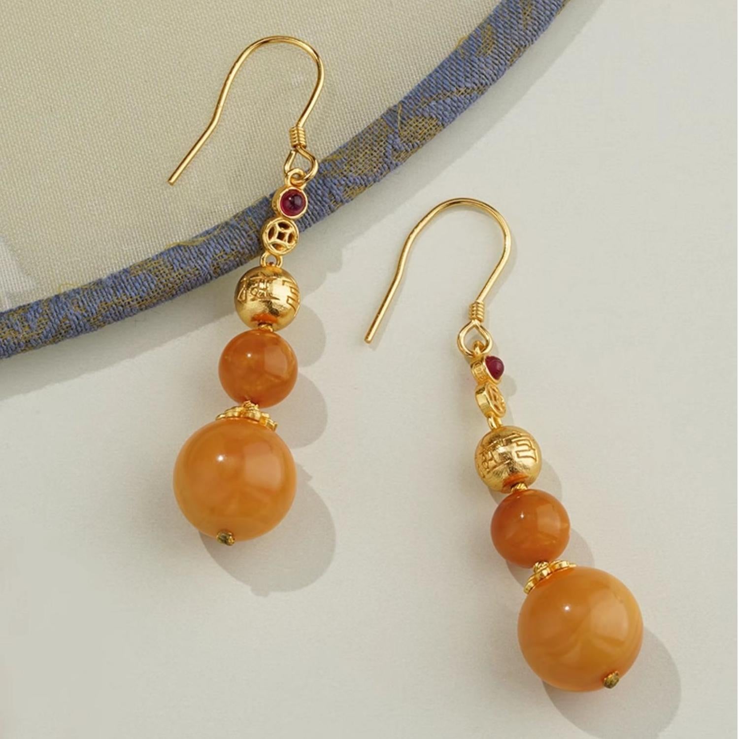 "Artisan-crafted amber earrings in 925 silver with cubic zirconia accents, inspired by Tibetan Buddhist art."