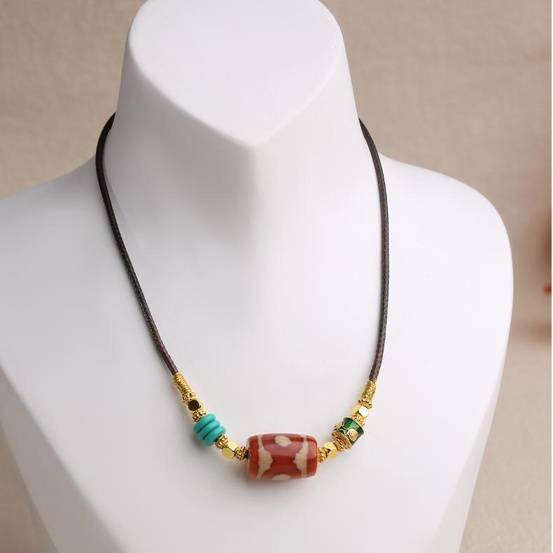 Artisanal Tibetan-inspired pendant showcasing a genuine agate Dzi bead with intricate copper metalwork and patina.