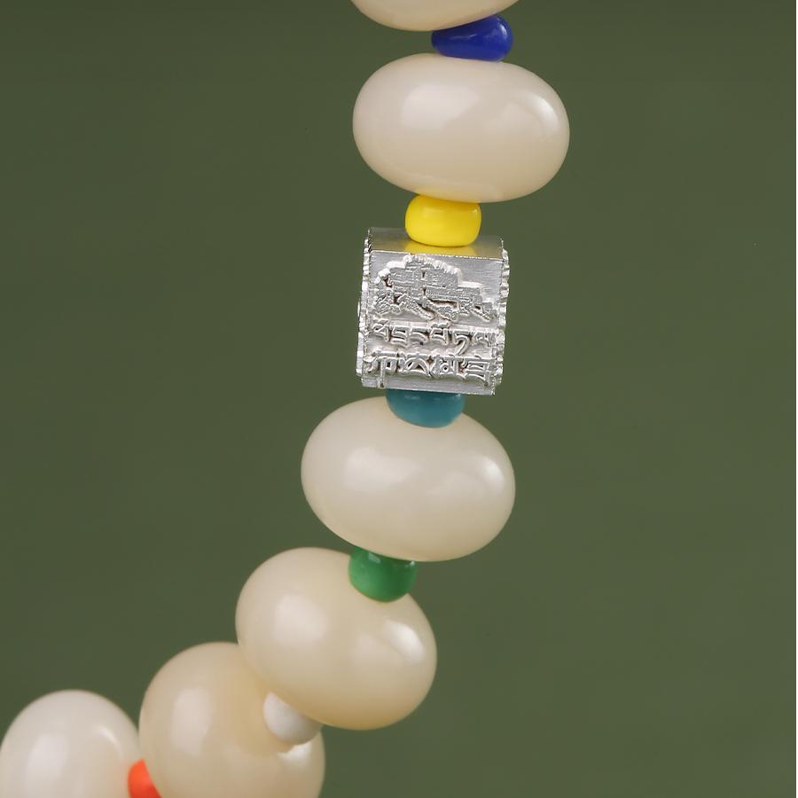 Close-up of a QIanlan Bodhi seed bracelet in Tibetan Buddhist jewelry culture. Features natural, light-toned beads meticulously hand-strung and adorned with delicate, hand-painted spiritual motifs using traditional dyes. This exquisite piece of jewelry art is perfect for daily mindfulness and meditation practice.
