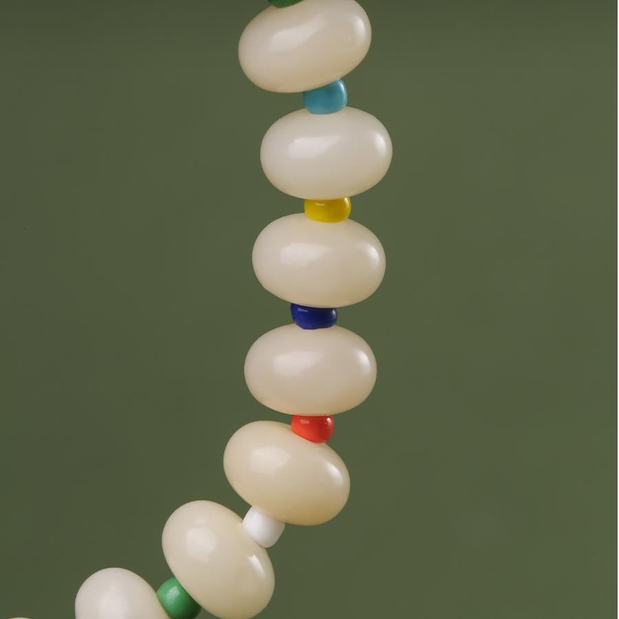 Detail shot highlighting the intricate hand-painted patterns on the QIanlan light-tone Bodhi bracelet. Each bead is a miniature canvas, showcasing the spiritual jewelry art and skilled craftsmanship inherent in Tibetan Buddhist culture.