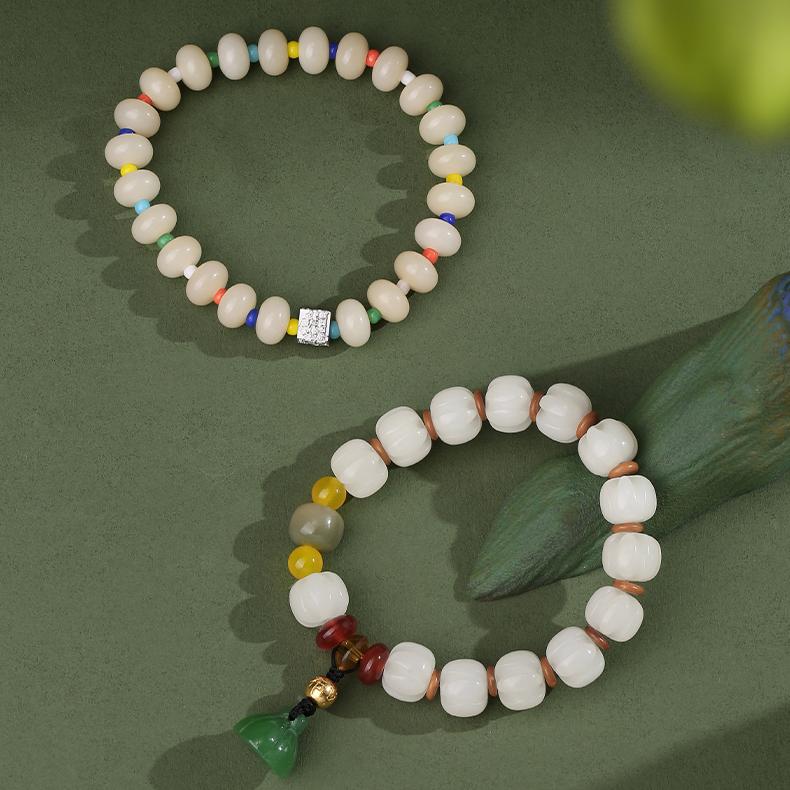 Flat lay of the Qionggu Rudraksha mala bracelet against a traditional Tibetan textile. The focus is on the meticulous hand-painting on each bead, representing a beautiful example of traditional Tibetan jewelry art for practitioners and collectors.