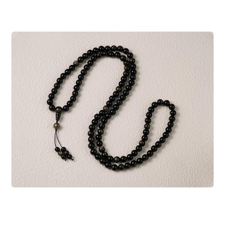 Ash mantra beads paired with golden obsidian in a Tibetan Buddhist prayer necklace.