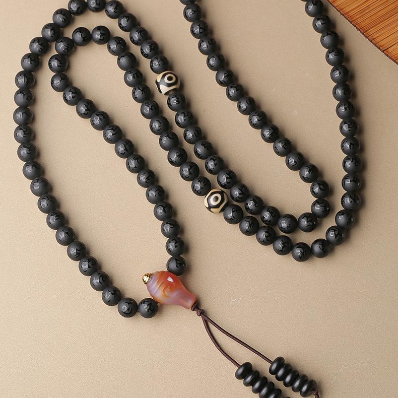 Tibetan Buddhist obsidian mala with mantra bead, dzi bead, and traditional jewelry craftsmanship.