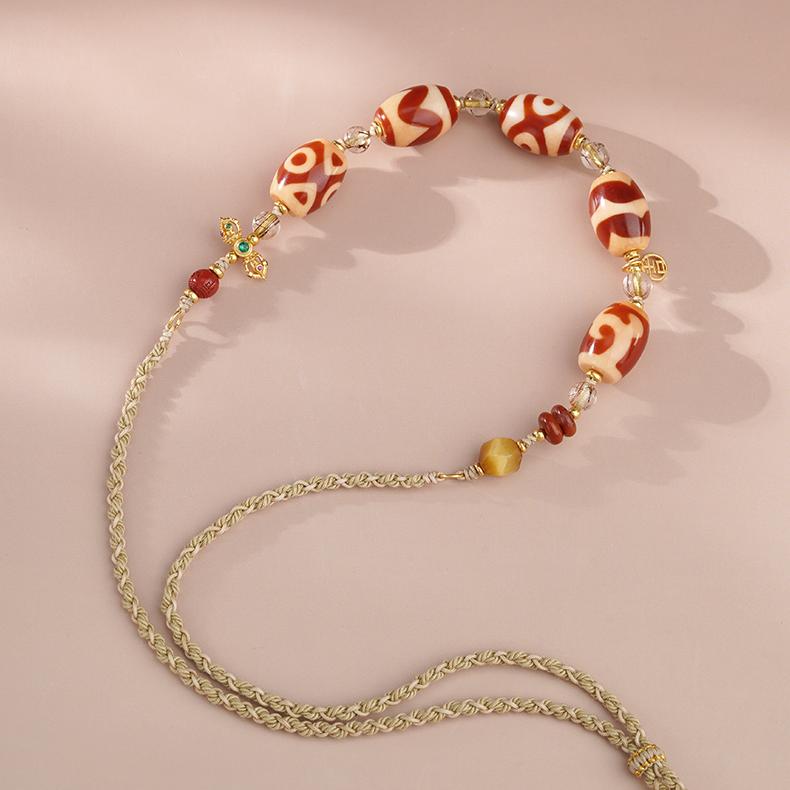 Tibetan Buddhist pendant combining red agate, tiger eye, and silver accents, handcrafted with sacred symbolism.