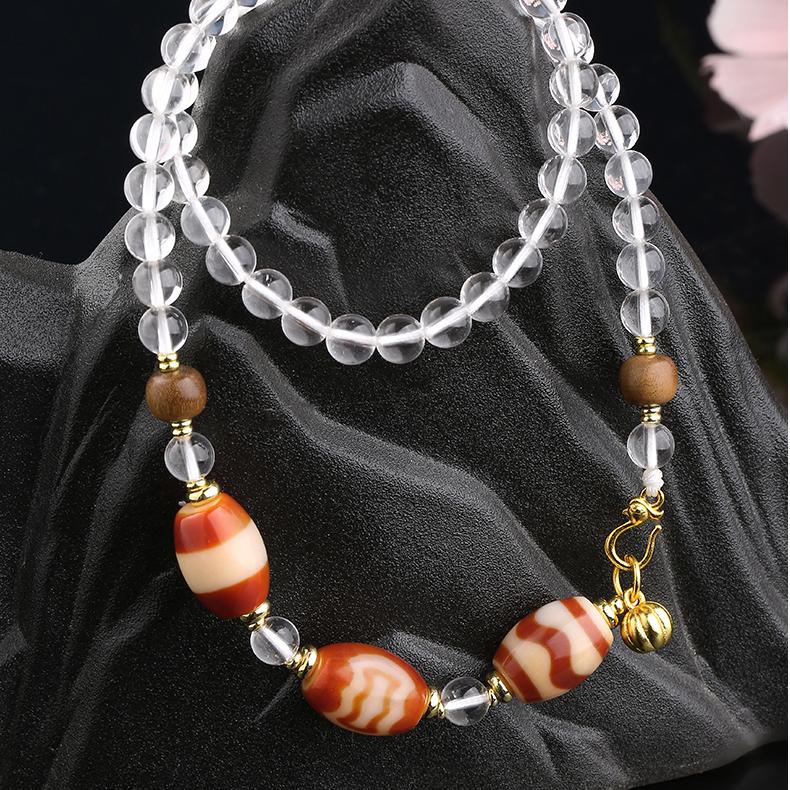 Tibetan Buddhist jewelry featuring red agate, white crystal, and copper details, symbolizing strength and spiritual balance.