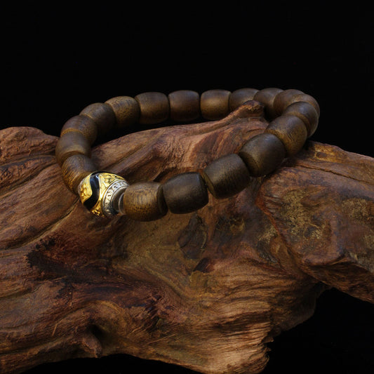 Natural agarwood bracelet with a tiger tooth Dzi bead and silver gilded accents, a sacred piece of Tibetan Buddhist sacrificial implements culture.