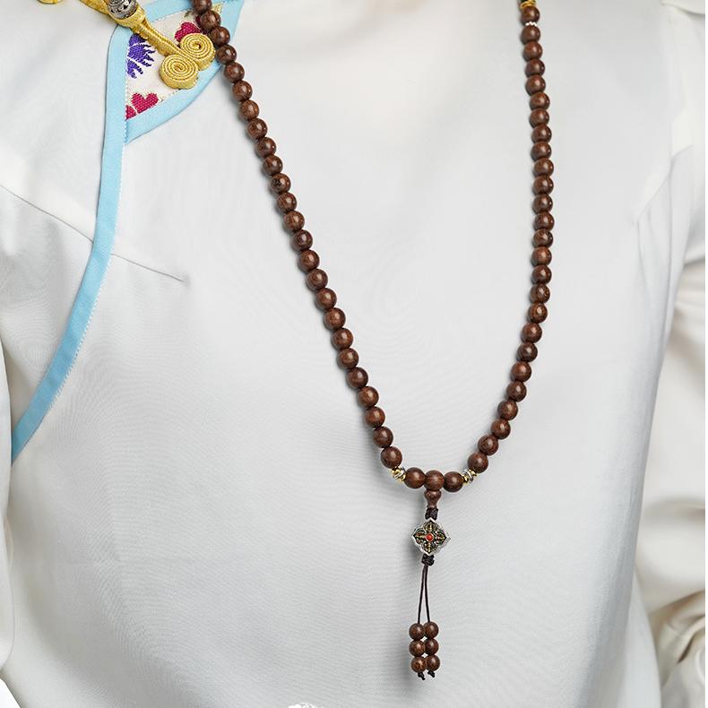 Artisanal Tibetan sandalwood mala with copper six-syllable mantra bead for spiritual practice.