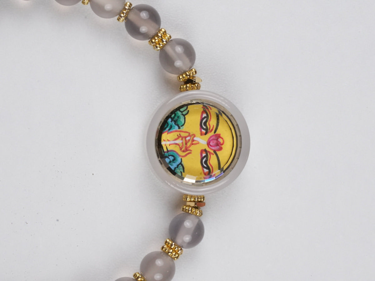 Handcrafted Tibetan-Buddhist Thangka bracelet depicting Yellow Dzambhala, the wealth deity of prosperity and success, rendered in traditional Buddha art technique