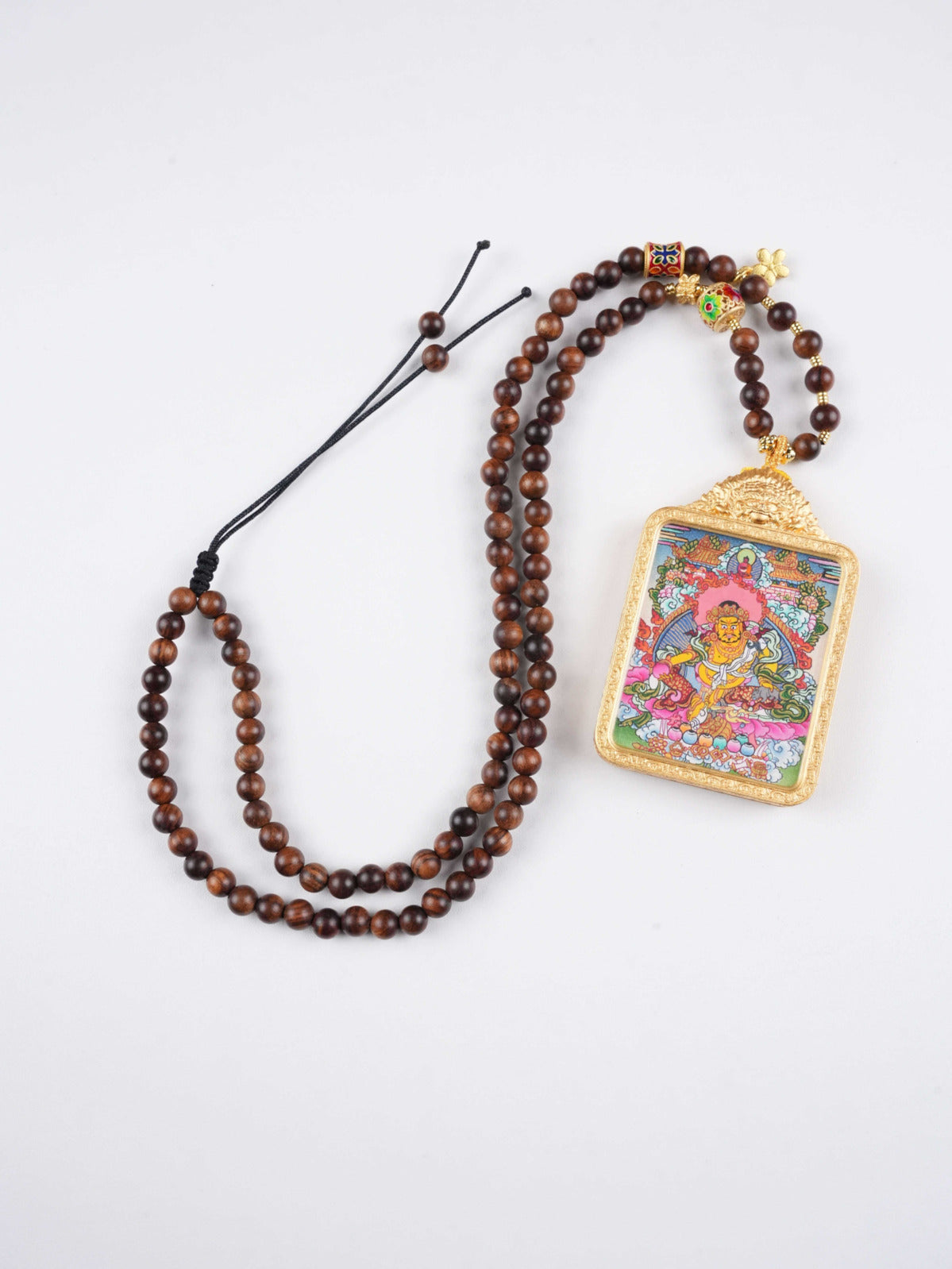 Detailed image of Yellow Jambhala Tibetan thangka pendant, highlighting the intricate hand-painted artistry.