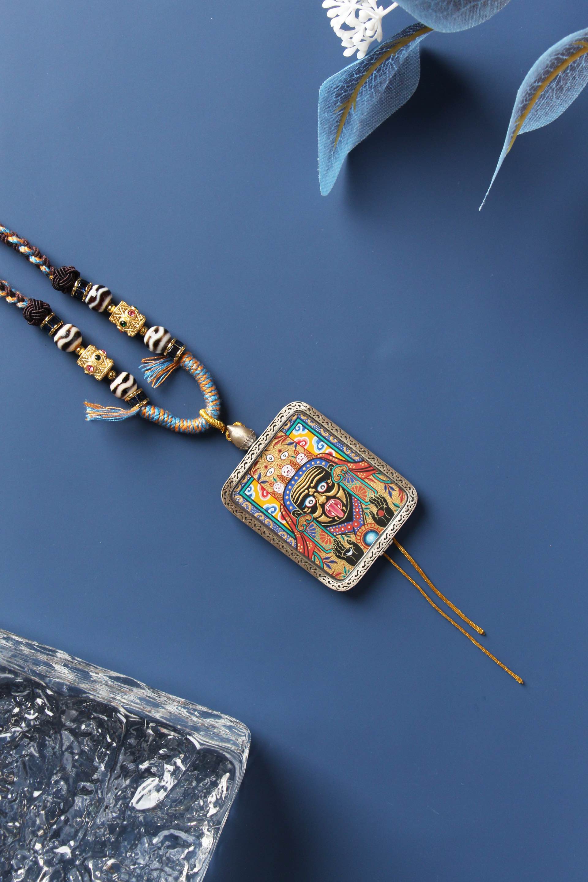Close-up of the Zaki Lhamo Thangka pendant featuring intricate hand-painted gold details, paired with a traditional Tibetan bead necklace.