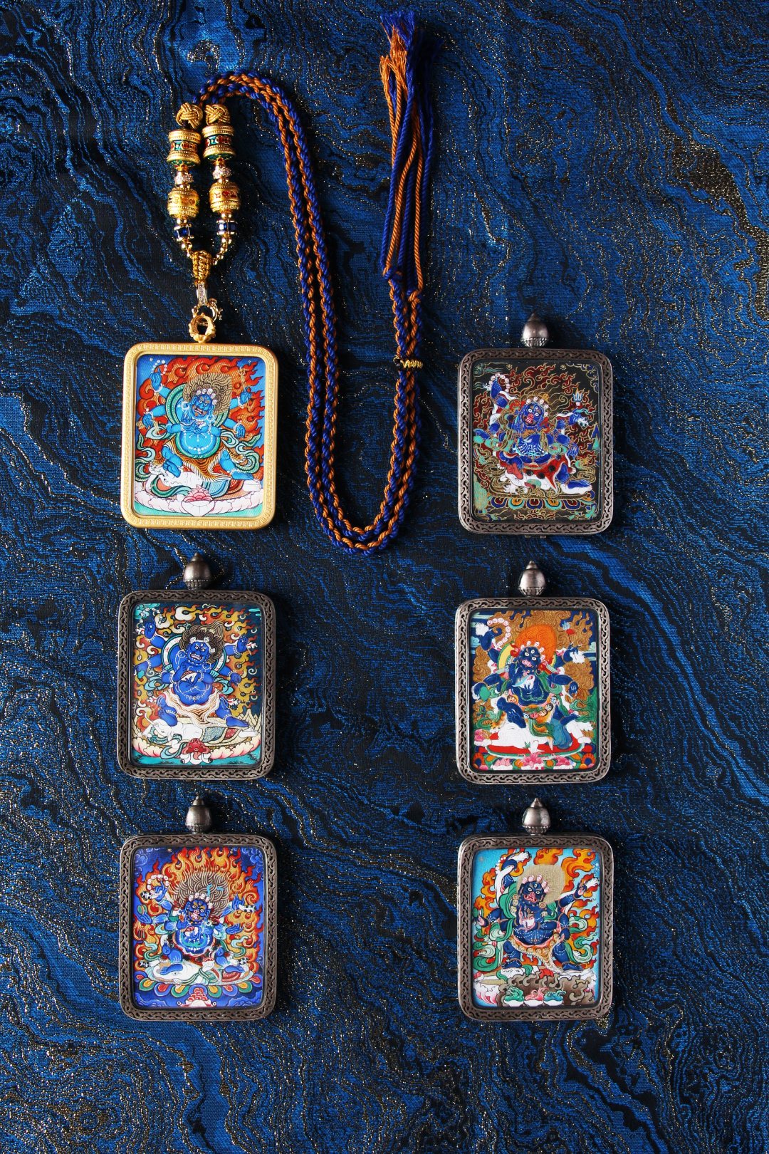A collection of sacred Tibetan deity pendants including Mahakala and other protectors in high-quality silver and copper frames.