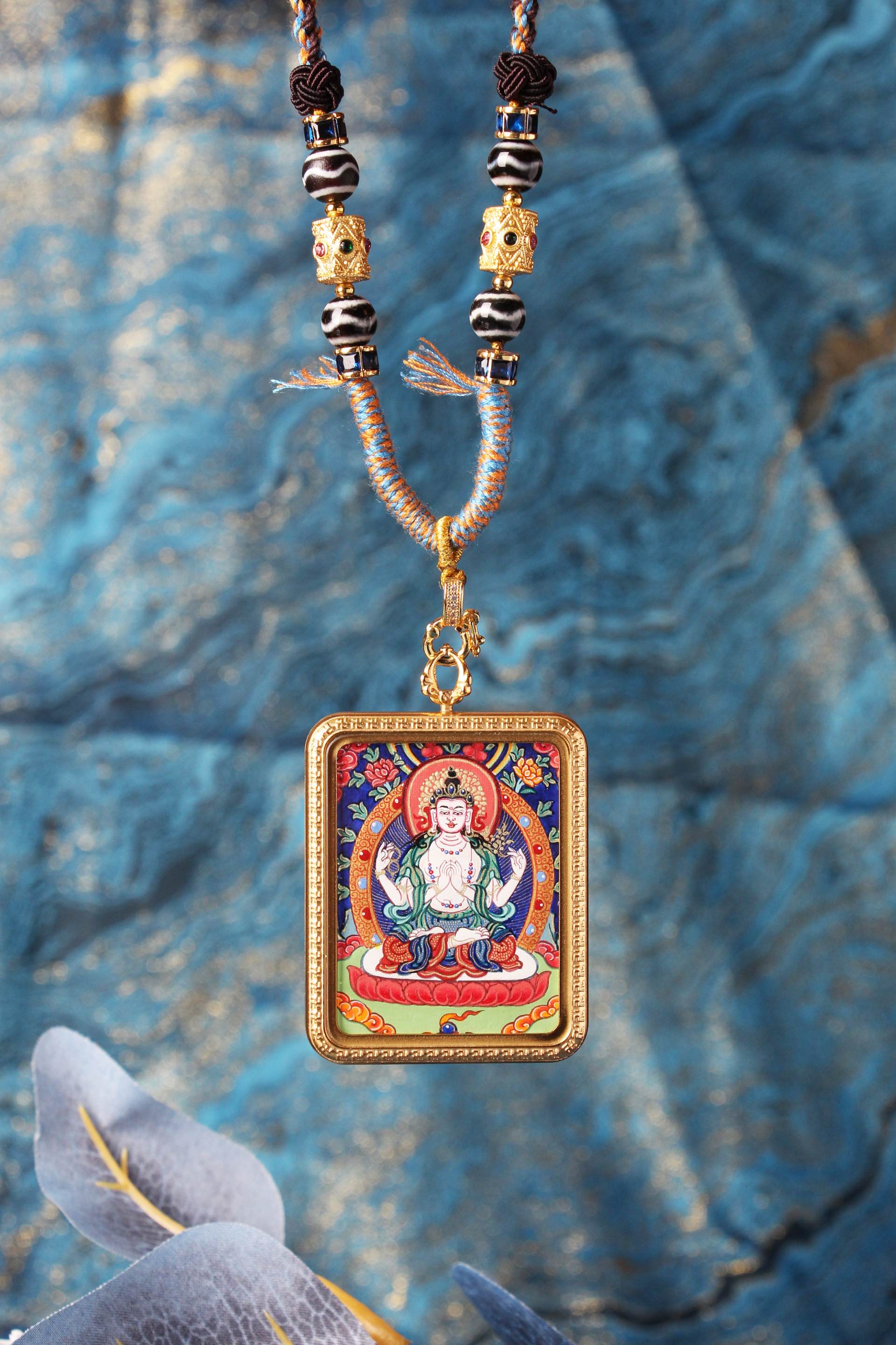 A hand-painted 3.5x4.5cm Four-Armed Avalokiteshvara Thangka pendant from Rebgong, featuring mineral pigments and a titanium steel frame.