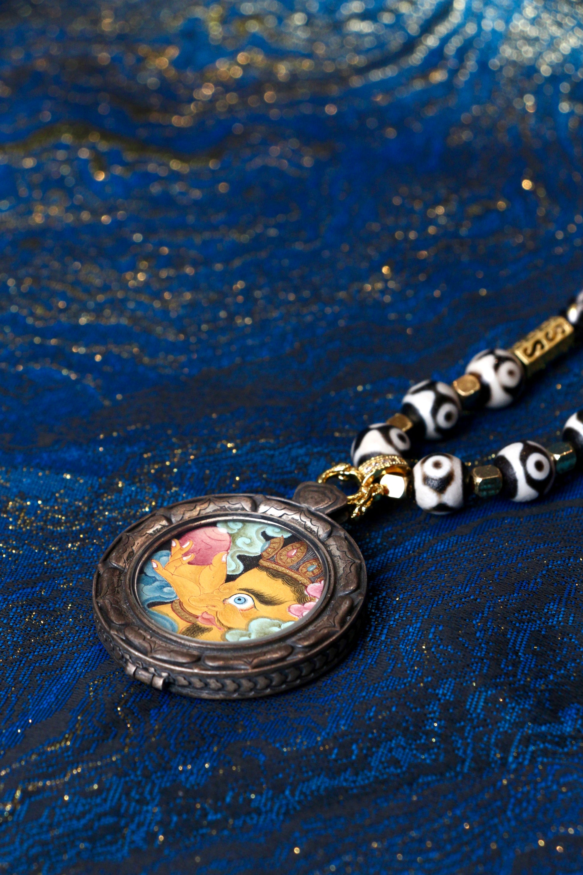 Macro view of the 2.5cm Yellow Jambhala Thangka, showing the vivid colors and fine lines created with traditional Tibetan mineral pigments.